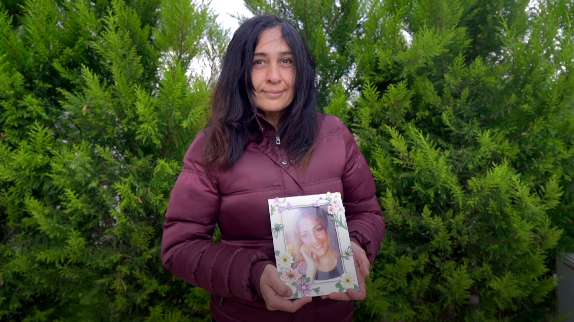 Sevgi, uma mulher turca de cabelos pretos, segura uma foto de uma mulher jovem