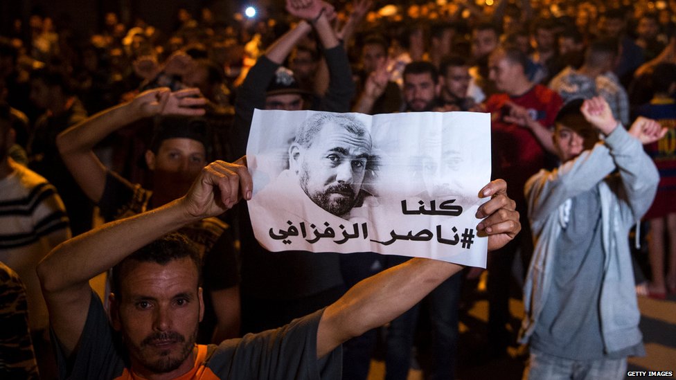 Протестующие держат изображение Зефзафи