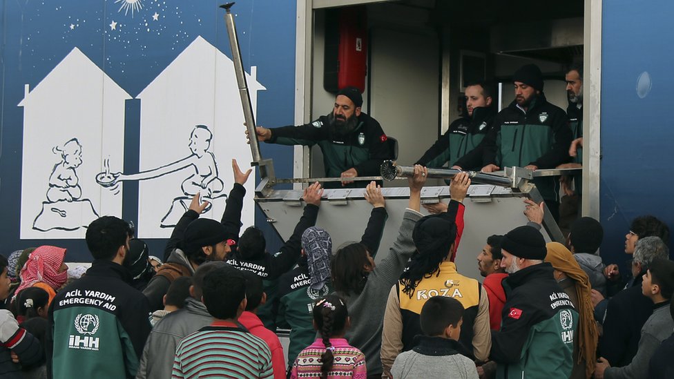 Сирийские беженцы получают помощь возле контрольно-пропускного пункта Баб-ас-Салам, напротив турецкой провинции Килис, 7 февраля