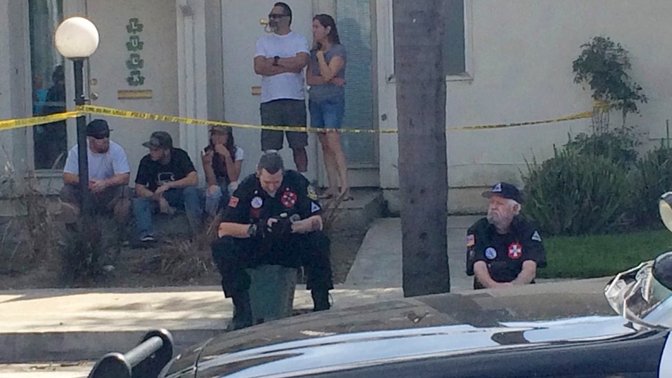 Члены KKK сидят на тротуаре после того, как митинг перерос в насилие