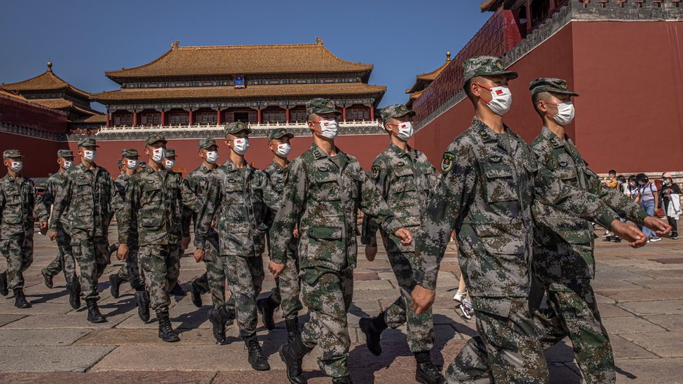 Chinese paramilitary police officers wearing protective face masks march past the entrance to the Forbidden City on National Day, in Beijing, China, 01 October 2021.