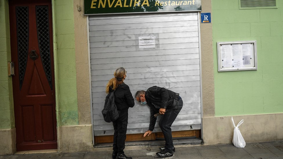 People close the shutter of a restaurant in Barcelona