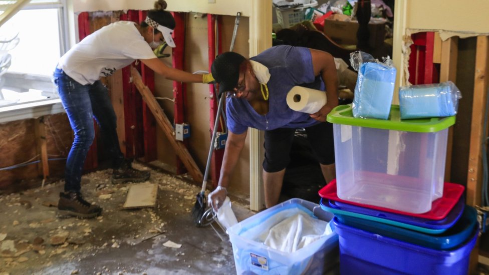 Волонтер работает с Барбарой Уилсон, когда она начинает убирать свой дом, затопленный ураганом Харви, в районе Хантервудс-Виллидж в Хьюстоне, штат Техас, 3 сентября 2017 г.