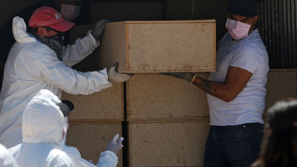 Trabajadores forenses descargan los ataúdes de víctimas no identificadas de la violencia en Ciudad Juárez, Chihuahua
