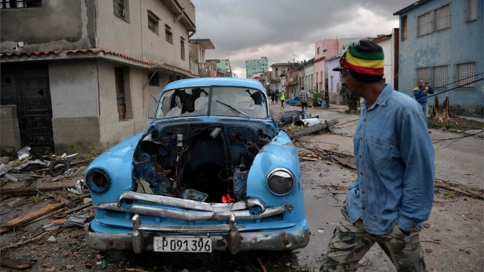 Un hombre camina frente a un auto antiguo destruido en La Habana. Un hombre camina frente a un auto antiguo destruido en La Habana.