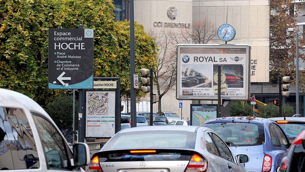Автомобиль проезжает мимо рекламы во французском городе Гренобль