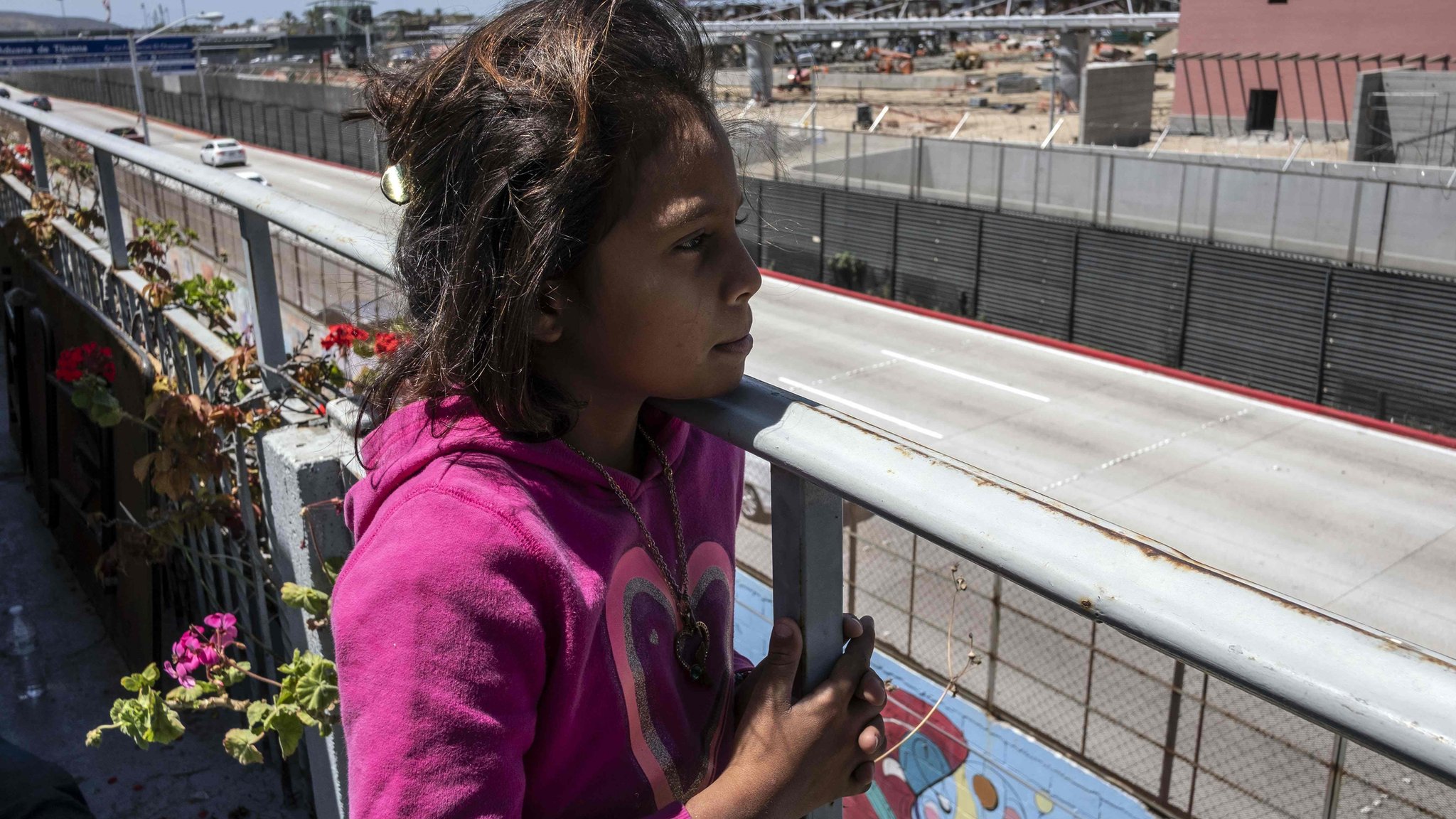Devojčica migrantkinja gleda preko zida