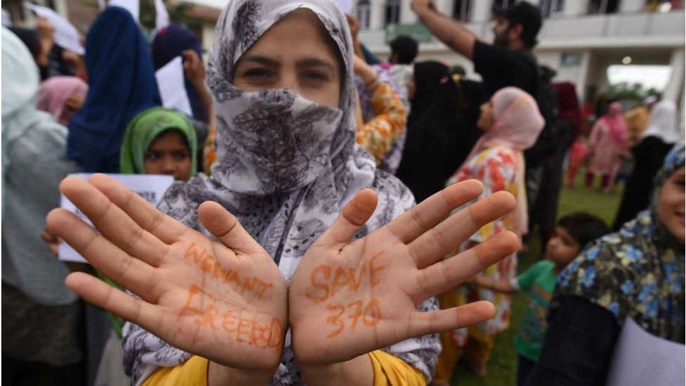 Женщина из Кашмира показывает свои раскрашенные хной руки с лозунгами «Мы хотим свободы» и «Спасаем 370 человек» во время акции протеста в Суре 16 августа 2019 года в Сринагаре, Индия.