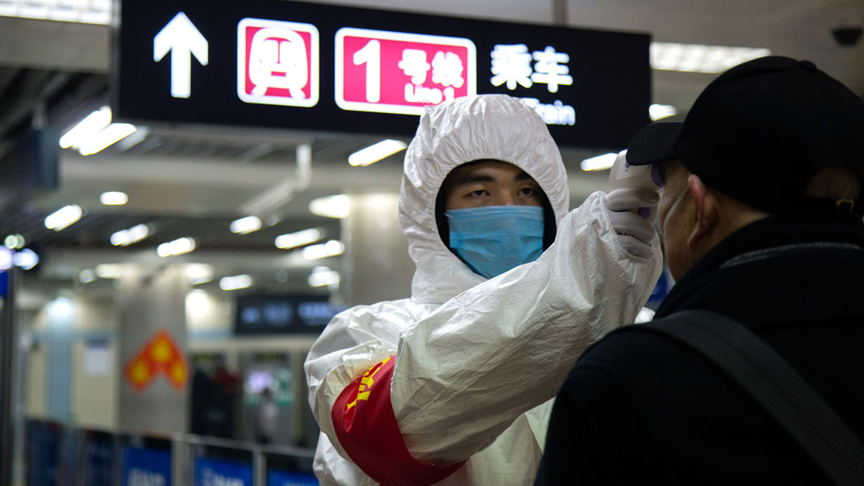 Медицинский работник проверяет температуру мужчины в Пекине