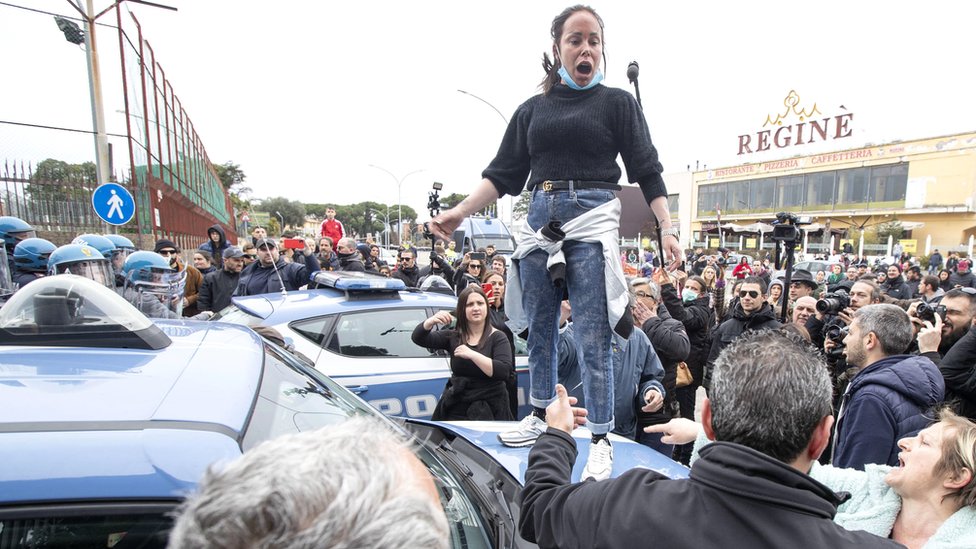 Родственники сокамерников протестуют, когда сотрудники правоохранительных органов стоят у тюрьмы Ребиббиа в Риме, где ранее вспыхнули беспорядки, 9 марта 2020 г.