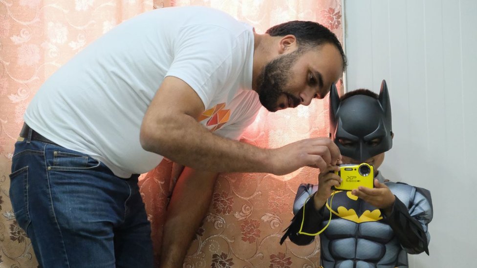 Работник благотворительной организации с ребенком-беженцем в костюме Бэтмена