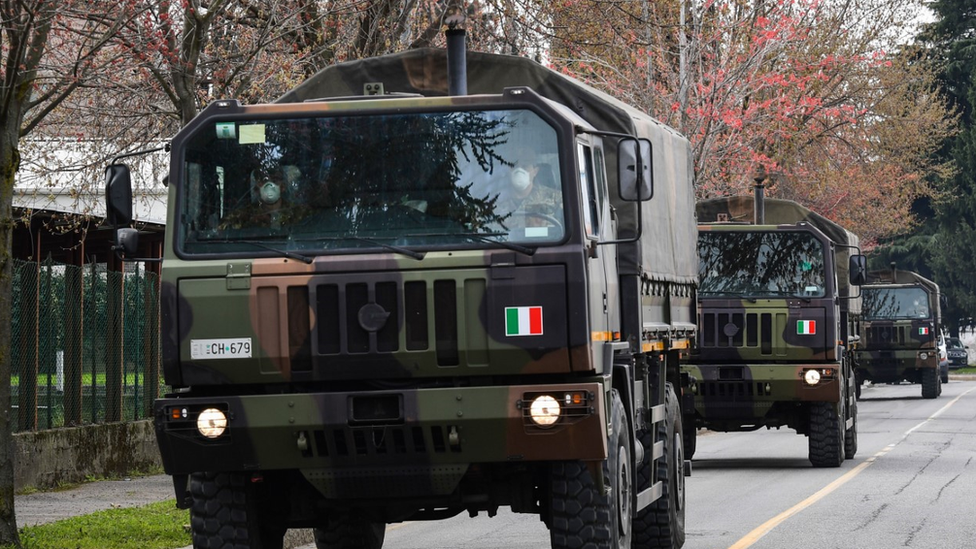 Caminhões do exército italiano em comboio pelas ruas de Bergamo, na Itália