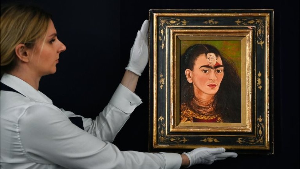Una empleada de la casa de subastas lleva el cuadro de Frida Kahlo 'Diego y Yo'