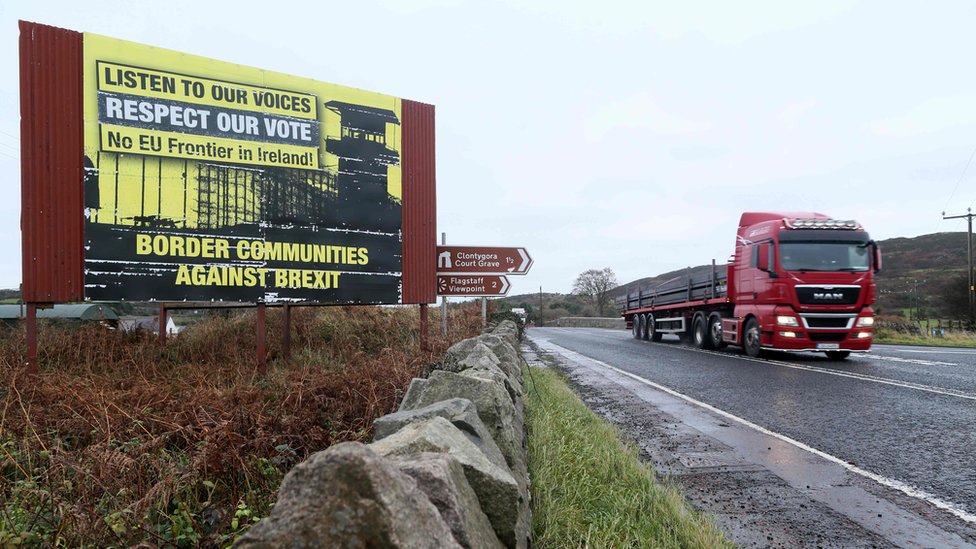 Грузовик проезжает мимо знака протеста против жесткой границы в Ирландии