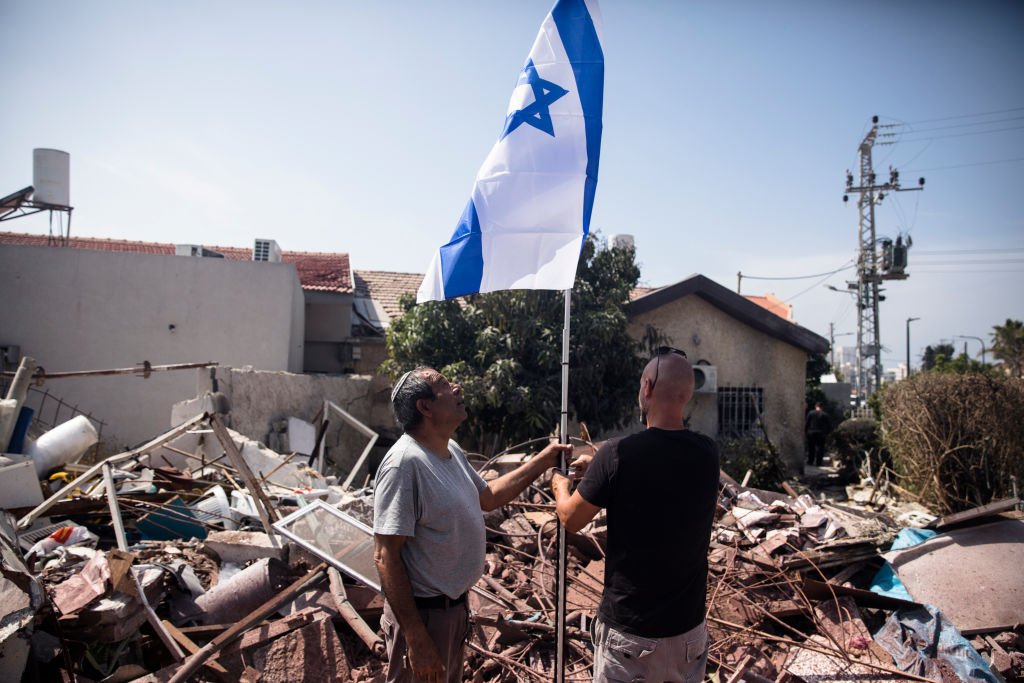 إسرائيليان يرفعان علم إسرائيل على أنقاض منزل