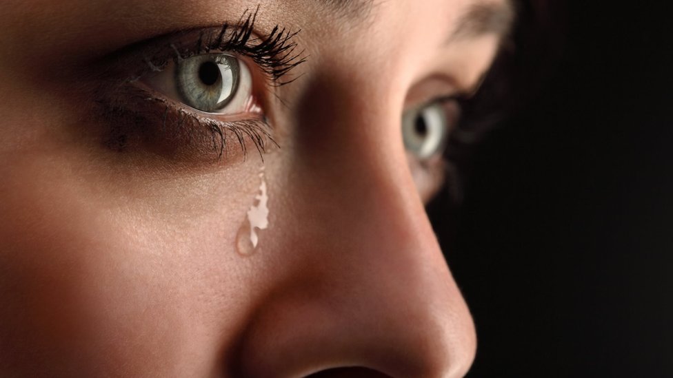 A woman's face with a tear running down her cheek