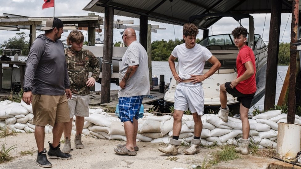 Волонтеры осматривают ряд мешков с песком в Жан-Лафитте, Луизиана