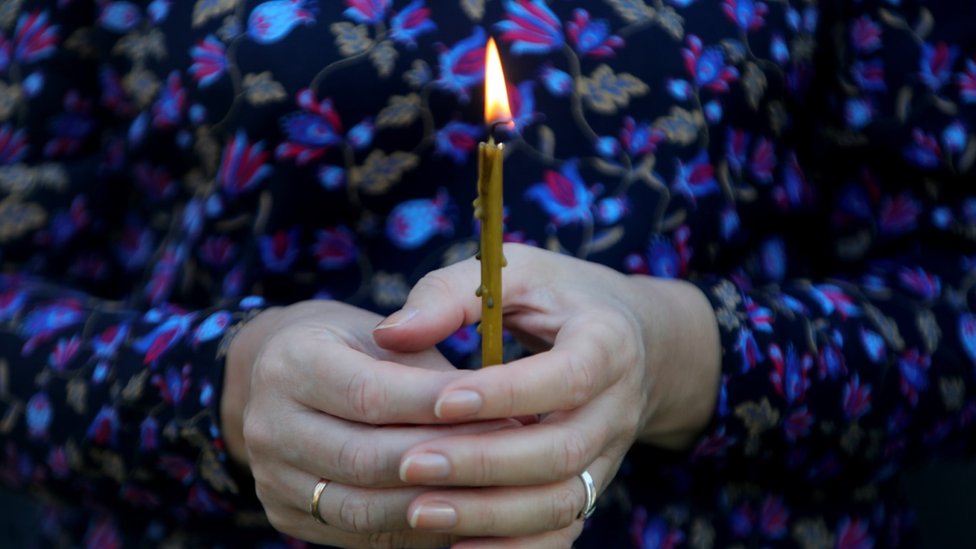 A woman holds a candle at a memorial in Ukraine
