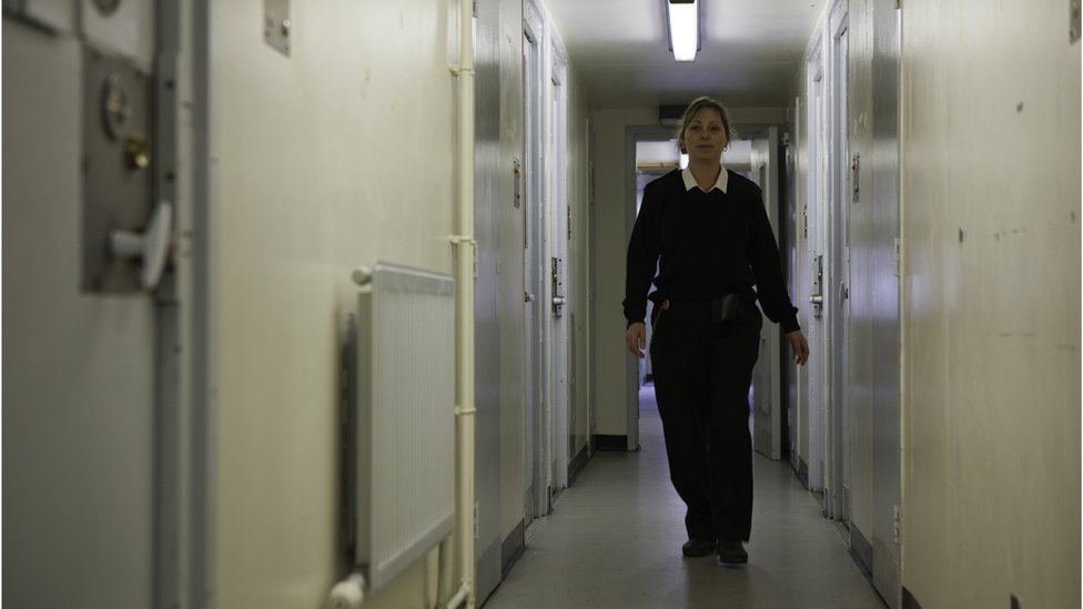 Женщина-тюремщик идет по коридору жилого крыла тюрьмы