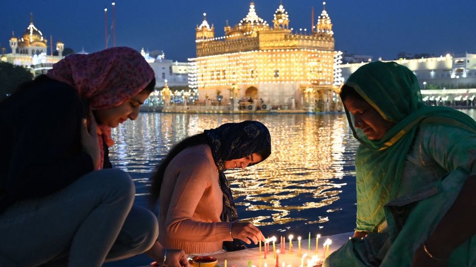 Devotees light candles while paying respect at the illuminated Golden Temple on the occasion of the Bandi Chhor Divas, a Sikh festival coinciding with Diwali, the Hindu festival of lights, in Amritsar on October 24, 2022. (Photo by Narinder NANU / AFP) (Photo by NARINDER NANU/AFP via Getty Images)