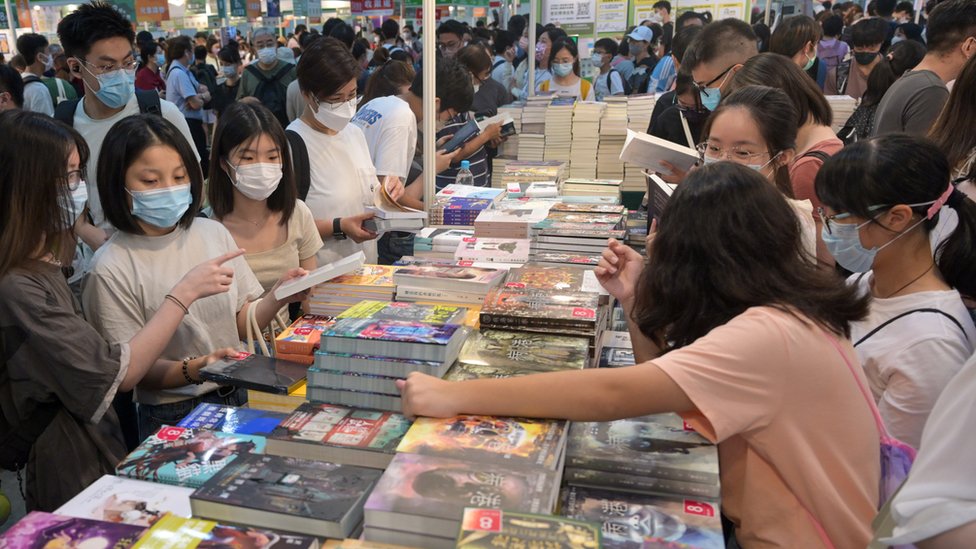 香港書展一書攤上一群讀者翻閲中文小說（中新社圖片21/7/2022）