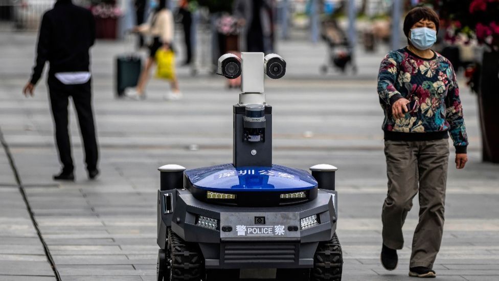 A police security robot drives among citizens in Shenzhen, China, March 2020