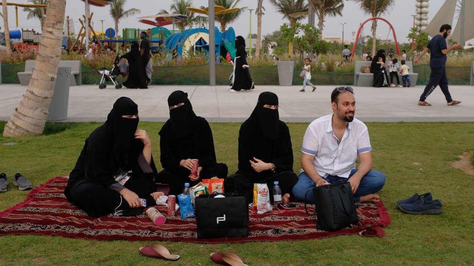 Tres mujeres completamente cubiertas de negro en Arabia Saudita, acompañadas de un hombre.