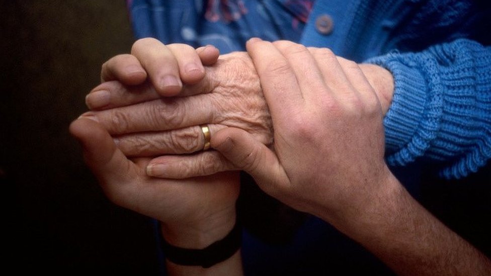 A younger person holding an older person's hands