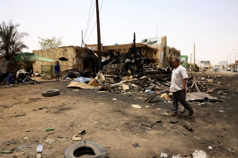اشتباكات السودان: المعارك مستمرة وبريطانيا تنفذ آخر رحلة إجلاء لرعاياها 1 رجل يسير وسط الدمار الذي خلفته القذائف بالقرب من مبان مدمرة في السوق المركزي في شمال الخرطوم، السودان، 27 أبريل/نيسان 2023.