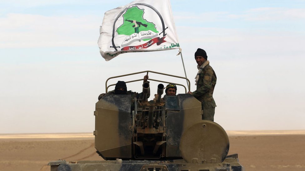 Бойцы стоят в башне боевой машины пехоты под флагом одного из отрядов Народной мобилизации, продвигаясь вместе с иракскими войсками через провинцию Анбар, 25 ноября 2017 г.
