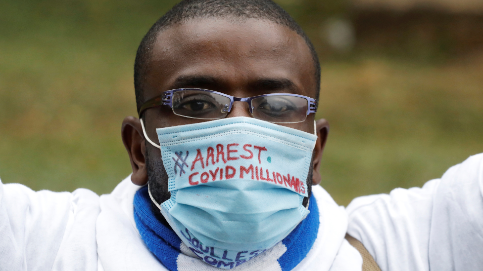 A Kenyan man wearing a mask with the words "arrest Covid millionaires" written on it - August 2020