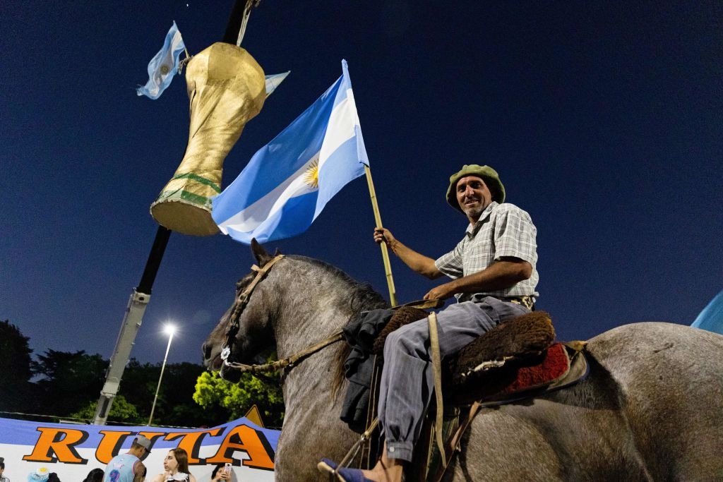 Un aficionado argentino montado en un caballo y con una bandera espera la llegada de la selección nacional de fútbol