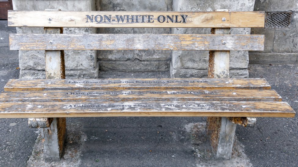 Un banco de madera en Ciudad del Cabo, Sudafrica, en el que se lee &quot;Solo no blancos&quot;