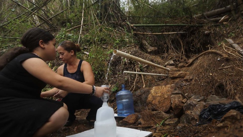 Mujeres cogiendo agua de un tubo