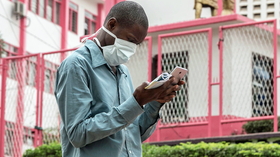 في نفس اليوم، رجل يرتدي قناعًا خارج مدخل المستشفى الرئيسي في عاصمة الكاميرون ياوندي، حيث يتم علاج مواطن فرنسي من فيروس Covid-19