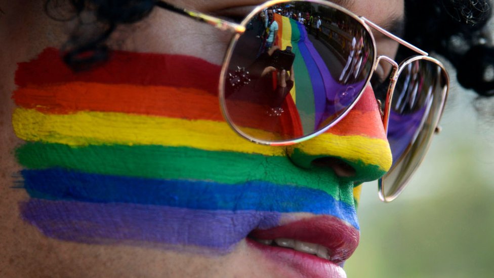 A person with their face painted with the LGBT flag