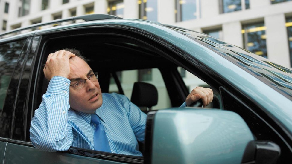 Un hombre con cara de angustia en un atasco de trafico.
