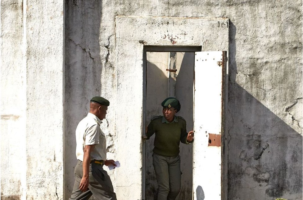 حراس السجن يقفون بجانب باب أبيض في سجن هراري المركزي.