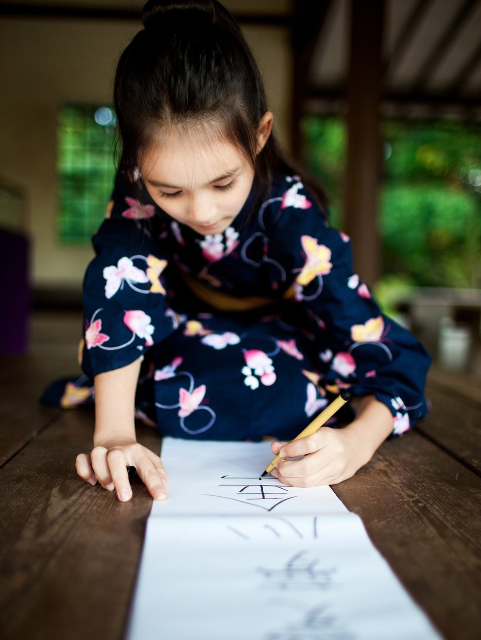 Los signos representan conceptos e ideas que se convierten en la manera de comunicación escrita entre los japoneses. niña escribe en un papel