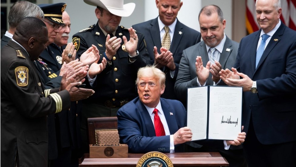 Presiden AS, Donald Trump menunjukkan surat perintah eksekutif untuk reformasi kepolisian di Gedung Putih.