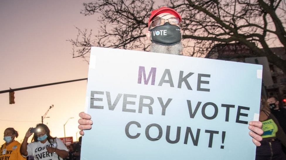 Un manifestante en Michigan sostiene un cartel que dice "Hagan que cada voto cuente"