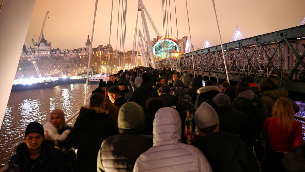 People walk along Hungerford Bridge during an anti-lockdown demonstration and a New Year"s celebration, amid the outbreak of the coronavirus disease (COVID-19), in London, Britain January 1