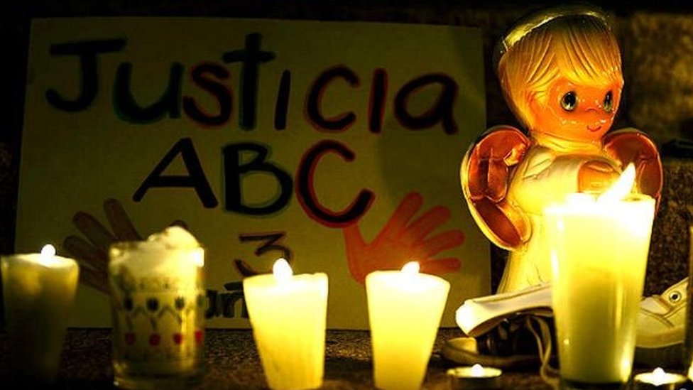 Una muñeca con un cartel que dice "Justicia ABC"
