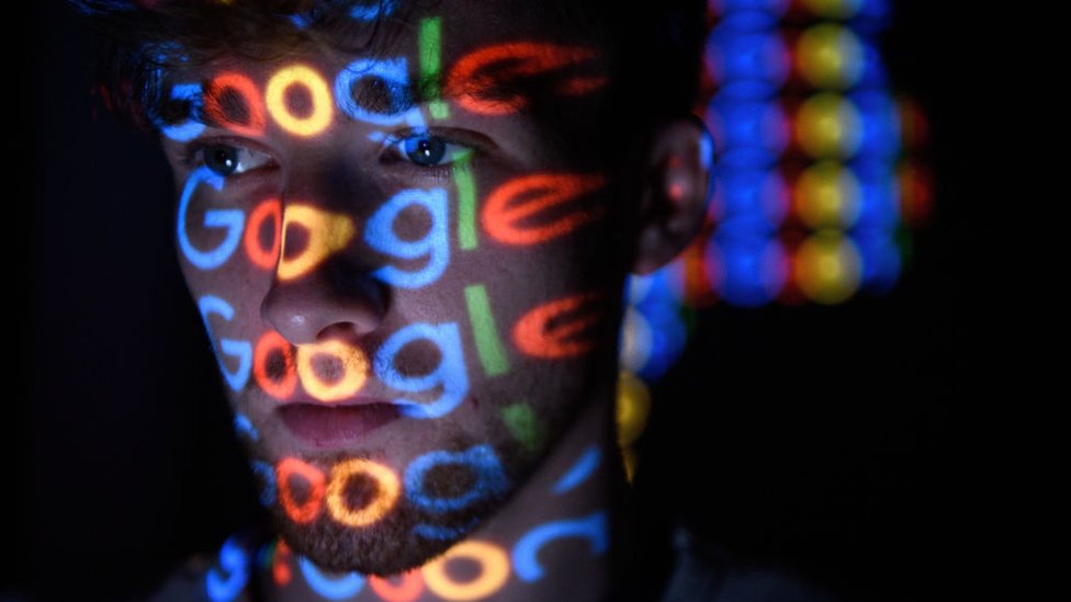 Yüzüne Google logosu yansıyan bir genç