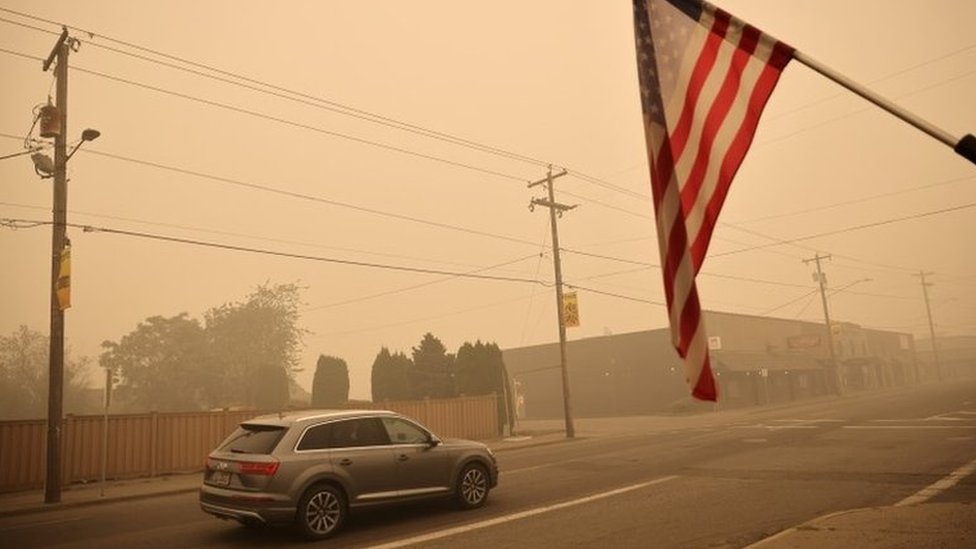 Автомобиль и флаг США в задымленном городе Молалла, штат Орегон