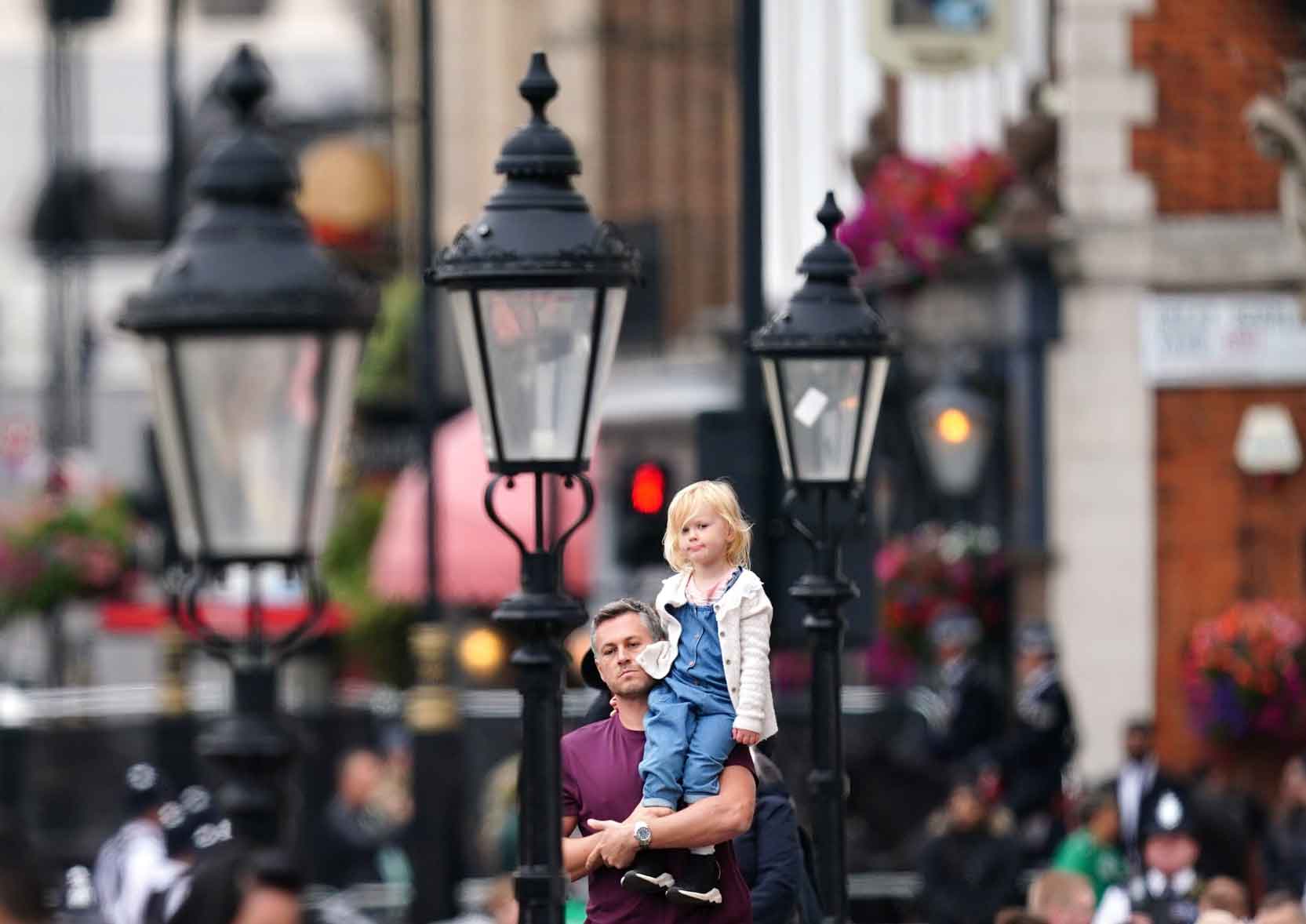 A young girl is held up by her father for a better view of the procession.