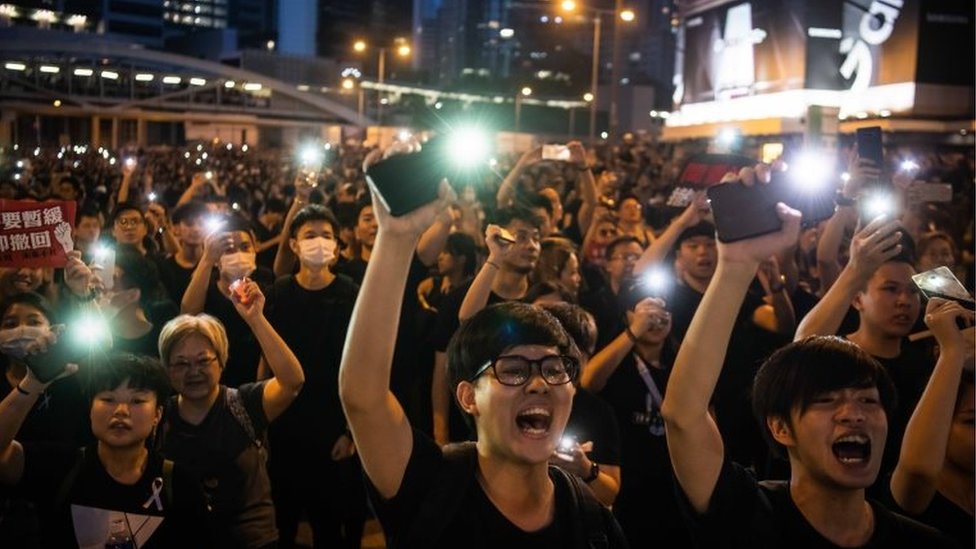 Протестующие светят фары от своих мобильных телефонов во время митинга против спорного предложения закона о выдаче 16 июня 2019 в Гонконге,