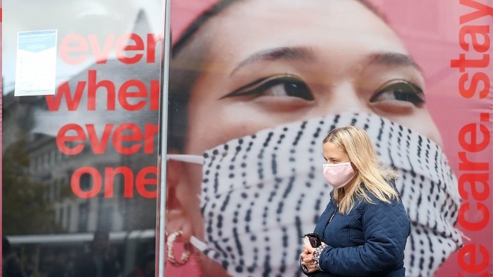 Mulher anda na rua usando máscara em Manchester