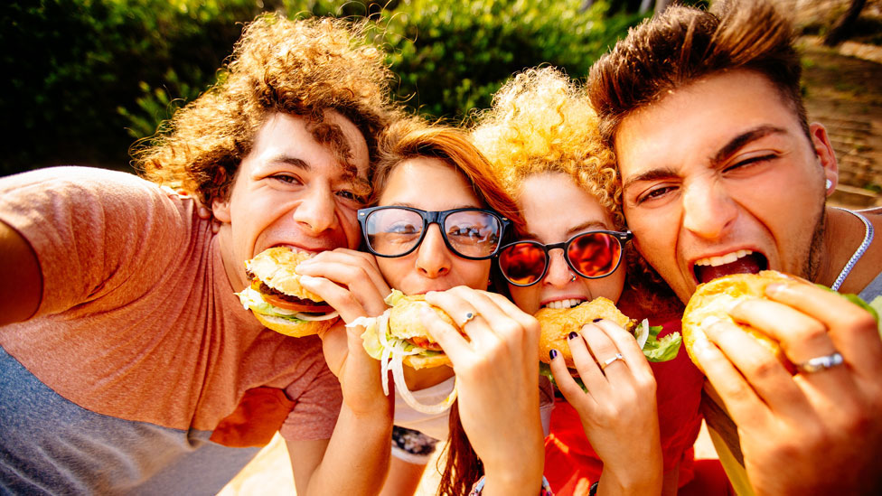 Un grupo de jóvenes comiendo hamburguesas.