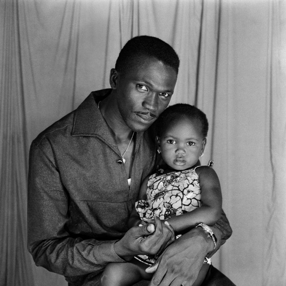 A man and baby girl pose for the camera in the photographer's studio.